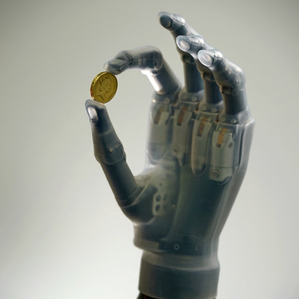 Prosthetic hand holds a coin between the index finger and thumb