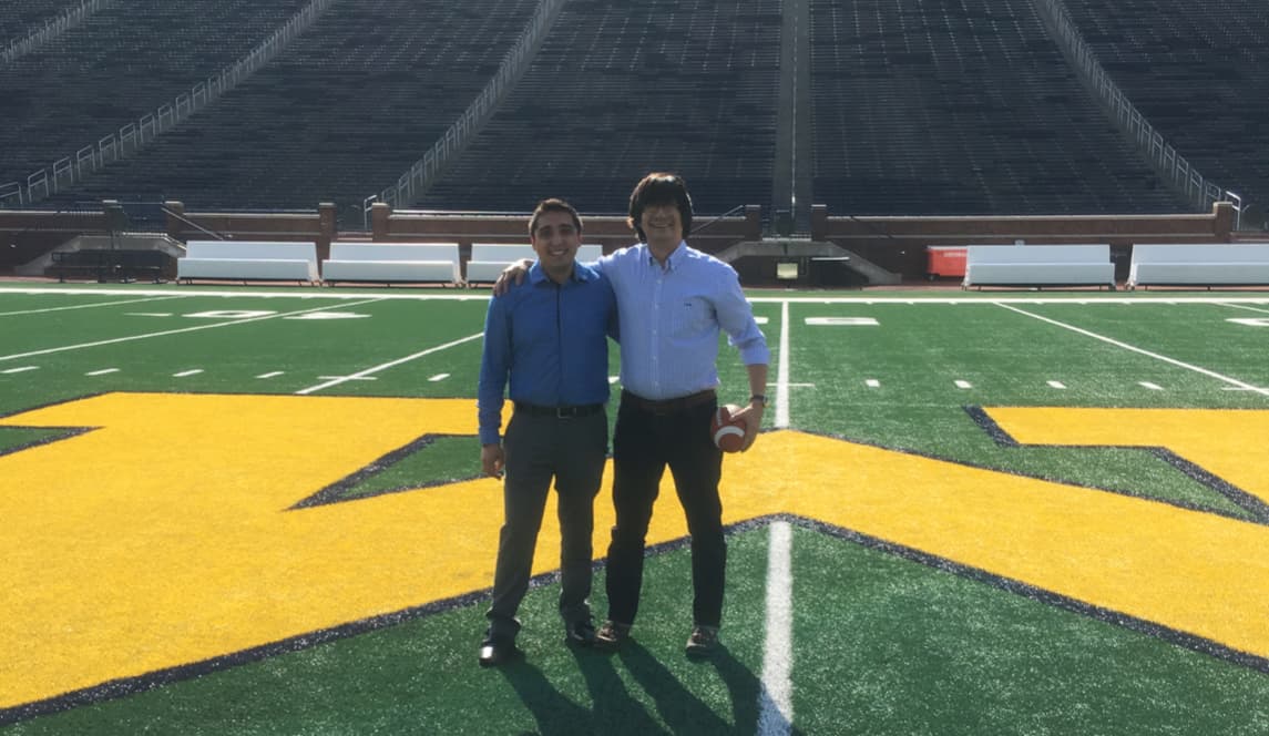 Carlos Aguilar and a student on the U-M football field